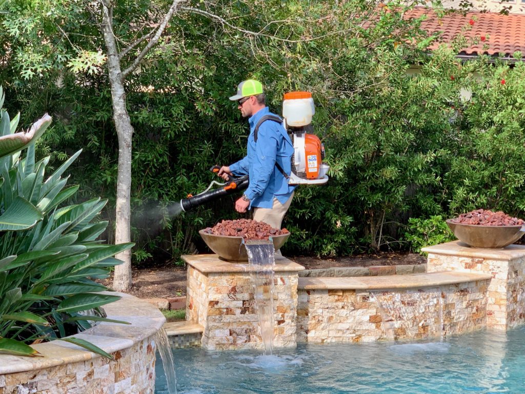 Pest control technician applying mosquito barrier spray in Fulshear, TX