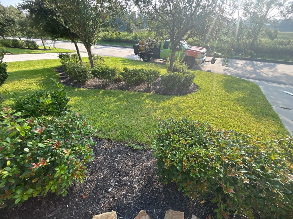 Lawn Care Stafford: GreenGate Truck parked outside a house/yard with green grass and clean, mulched flower beds