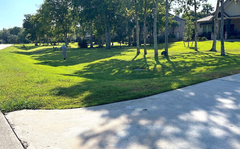 Large green front lawn with a greengate technician treating for sod webworms and grub worms