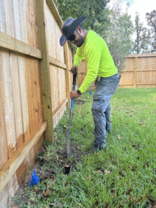 Sprinkler technician completing a repair near a fenceline