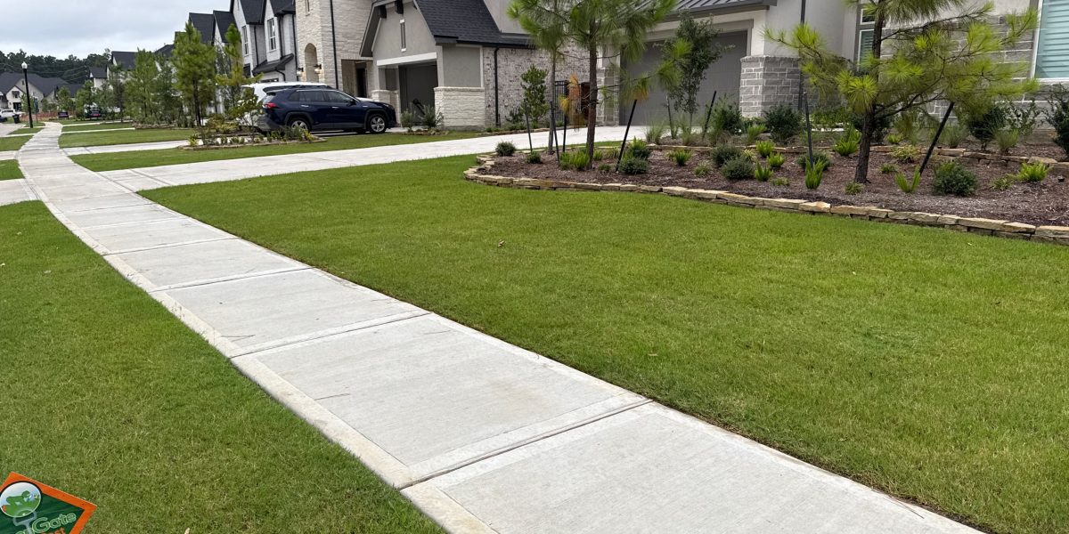 Green front lawn with a greengate sign in the grass after lawn fertilizer plan